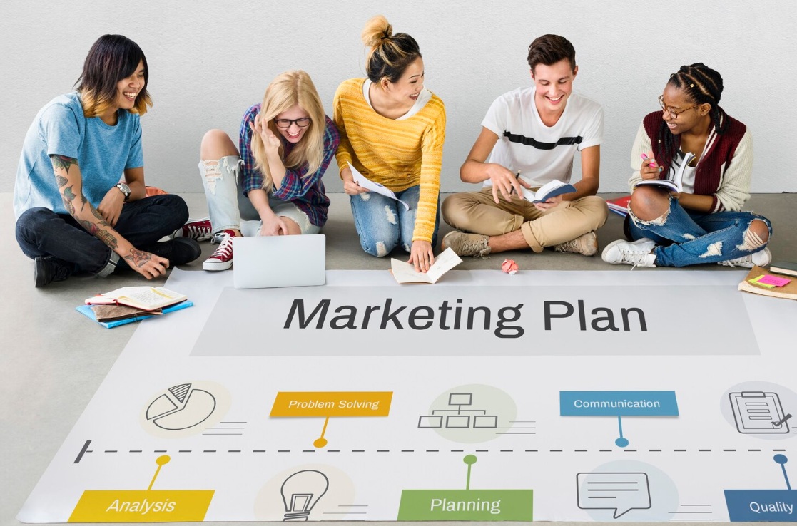 Five young people sitting next to a digital marketing plan concept