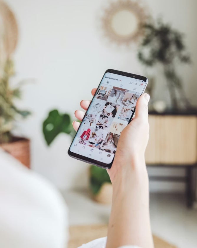 Hand holding a smartphone displaying Instagram images