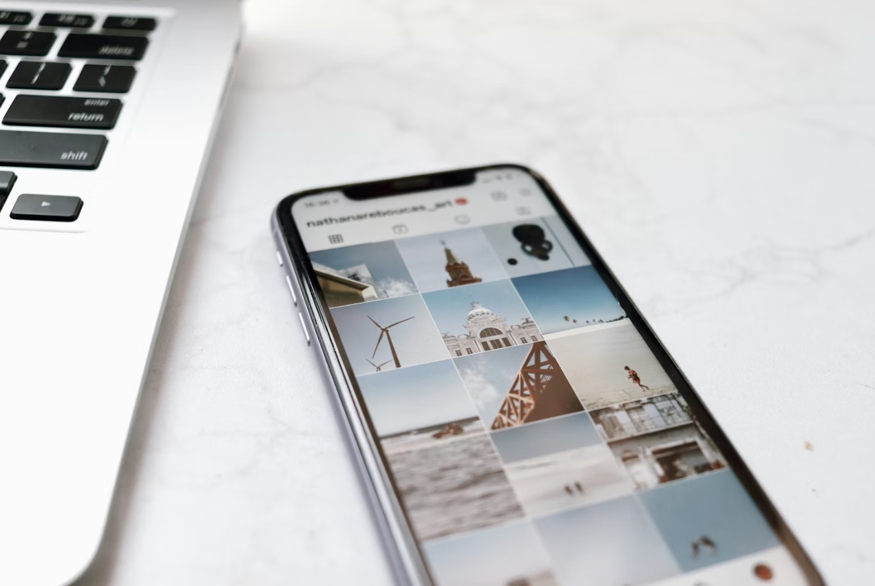 Smartphone displaying Instagram pictures next to a laptop