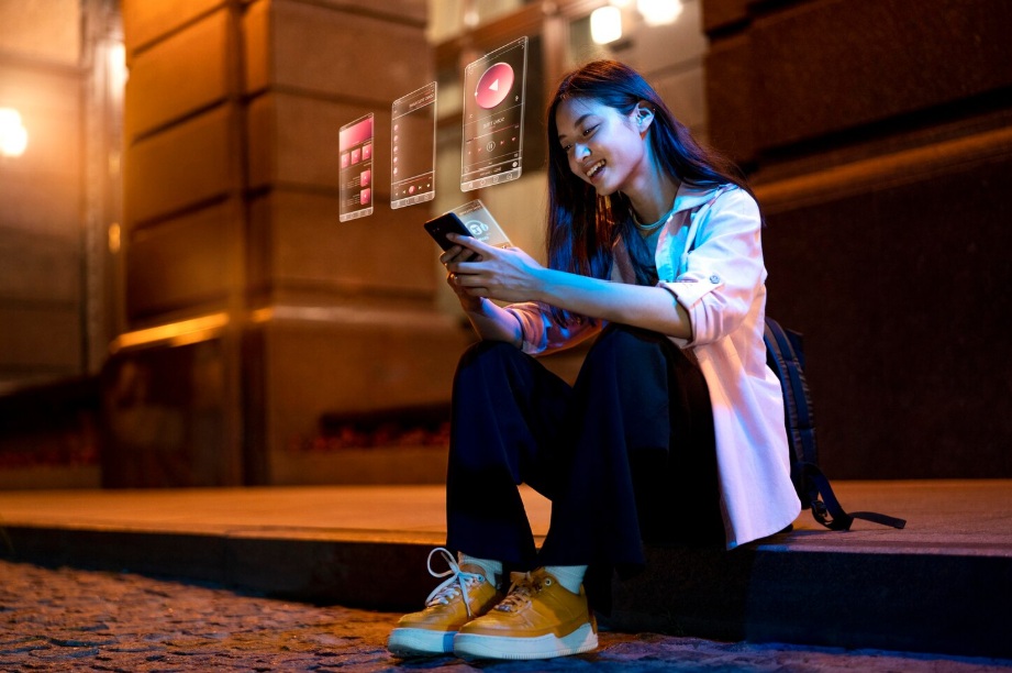 Asian young woman sitting on the sidewalk while holding a smartphone