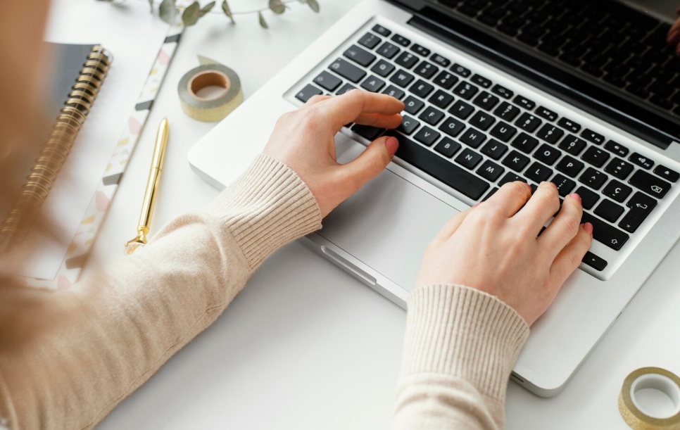 Focus on woman's hands typing on her laptop's keyboard