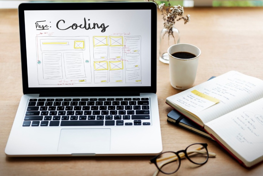 Page Speed Optimization 4 Office desk with stationaries and a laptop displaying web code and wireframe