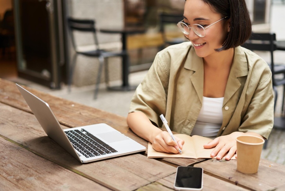 Young Asian woman taking notes from her laptop
